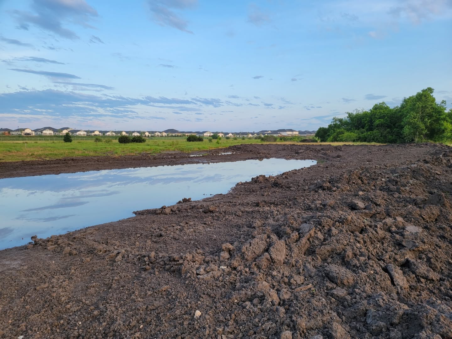 Earthen dam embankment under construction on a ranch tank